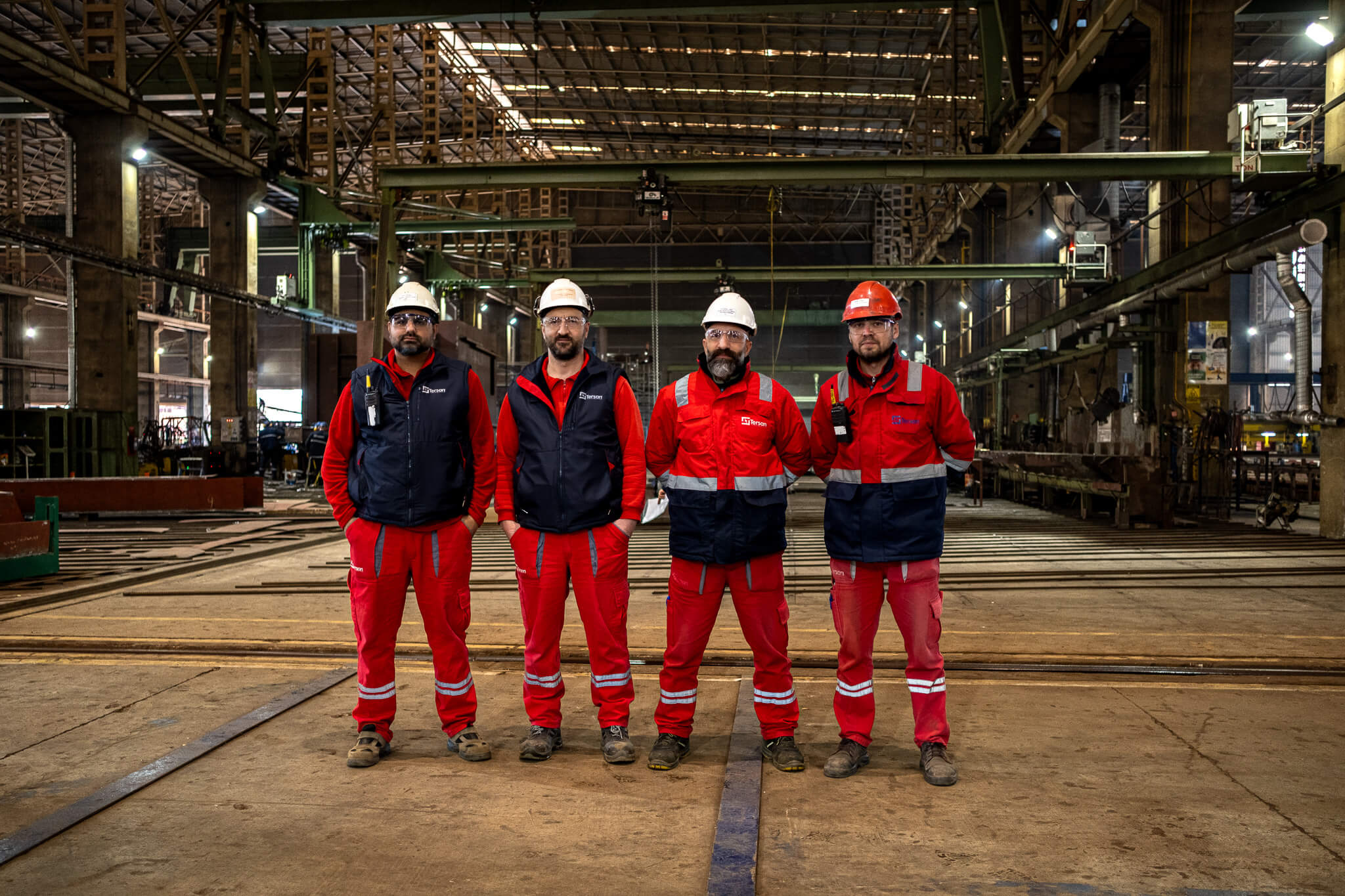 Tersanede dört çalışanın iş güvenliği kıyafetleriyle grup fotoğrafı