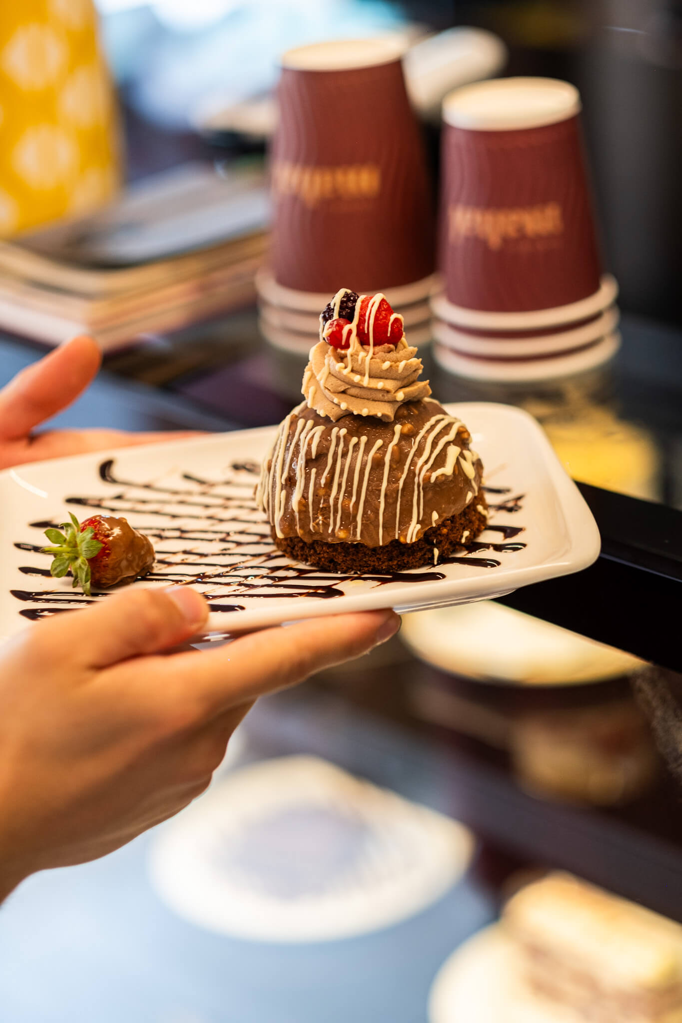 Çikolatalı tatlının elde tutularak sergilendiği kafe fotoğrafı