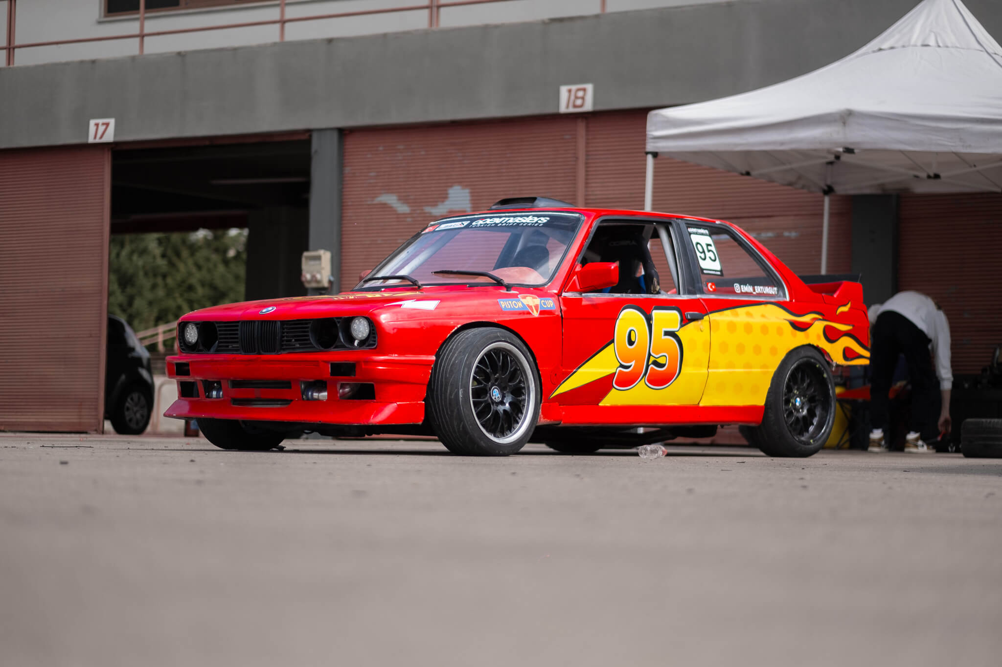 Kırmızı BMW E30 yarış otomobilinin pit garajı önünde fotoğrafı