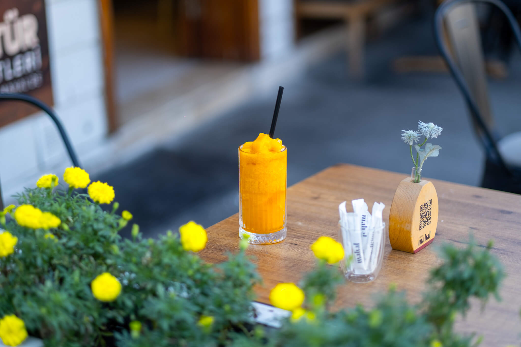 Mango smoothie içeceğinin çiçekli kafe masasında sunum fotoğrafı