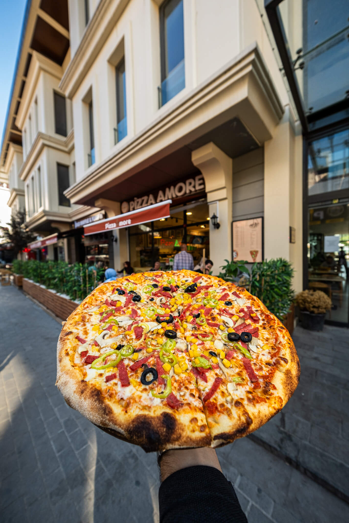 Restoran önünde elde tutulan pizzanın sokak fotoğrafı